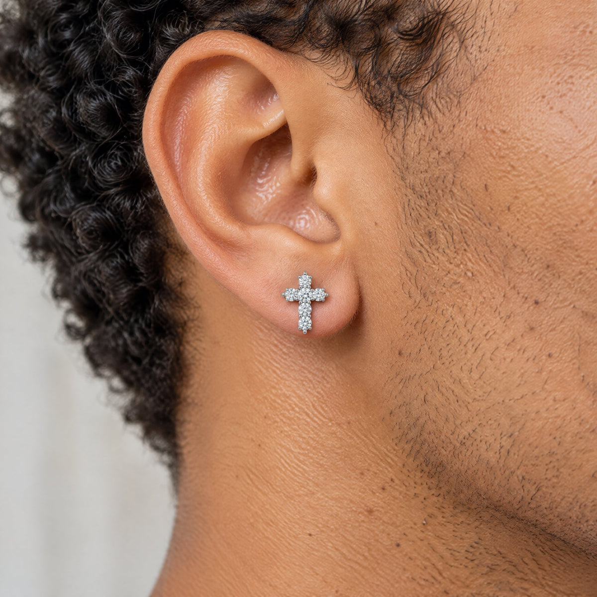 Cross stud earring worn on the earlobe