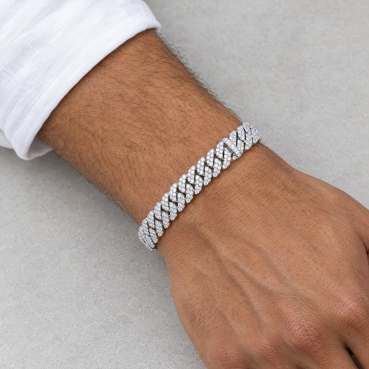 Man wearing a 10mm iced Cuban link bracelet below a white shirt cuff