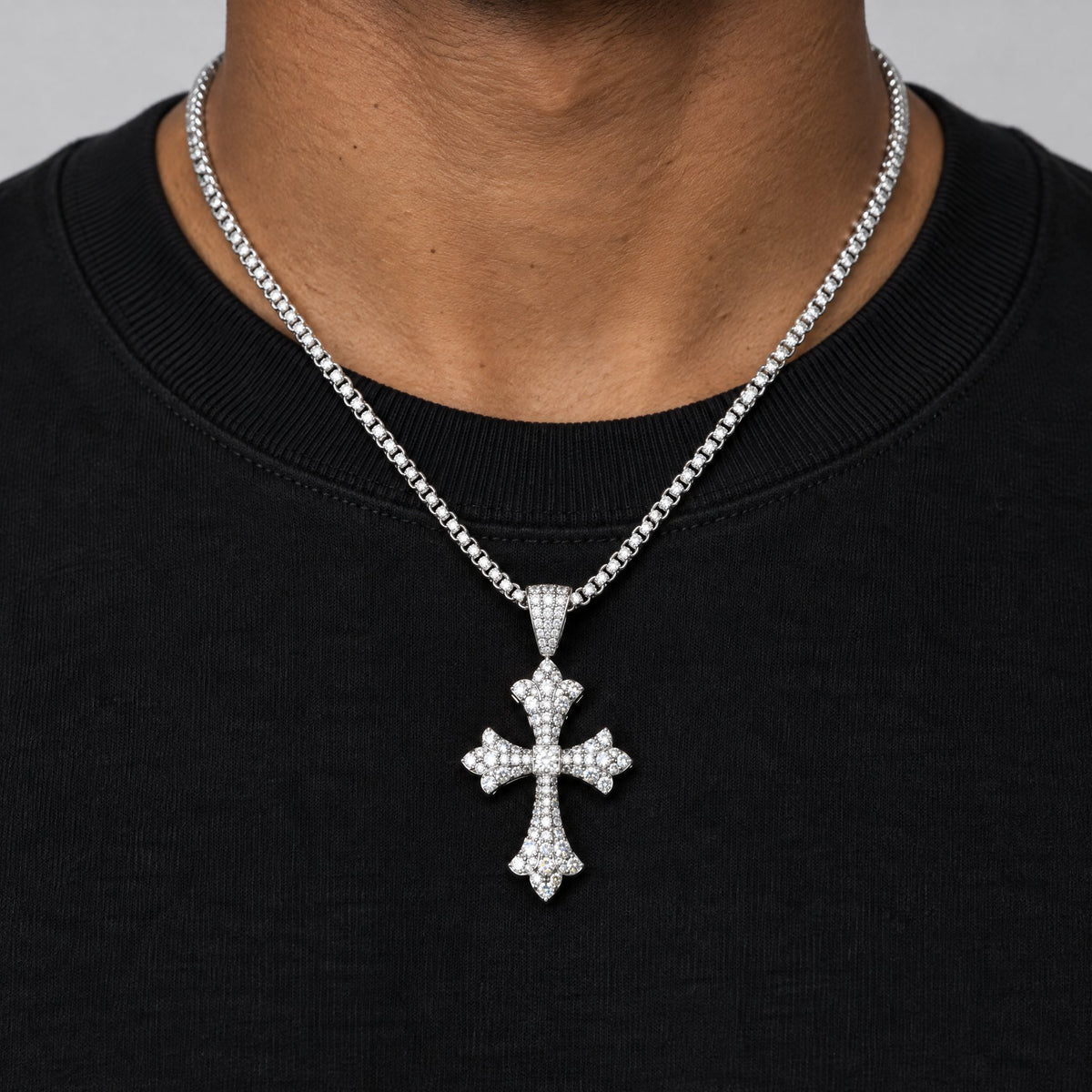 Man in a black T-shirt wearing the floral-tip cross pendant