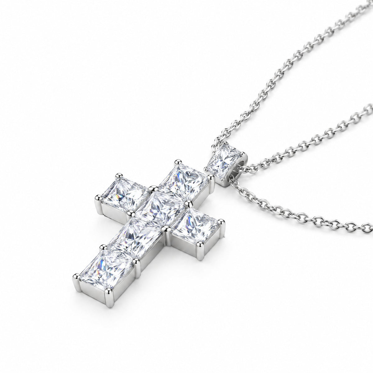 Slim cross pendant lying at an angle on its chain