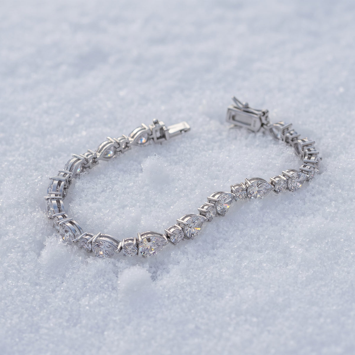 Pear-cut tennis bracelet lying on snow