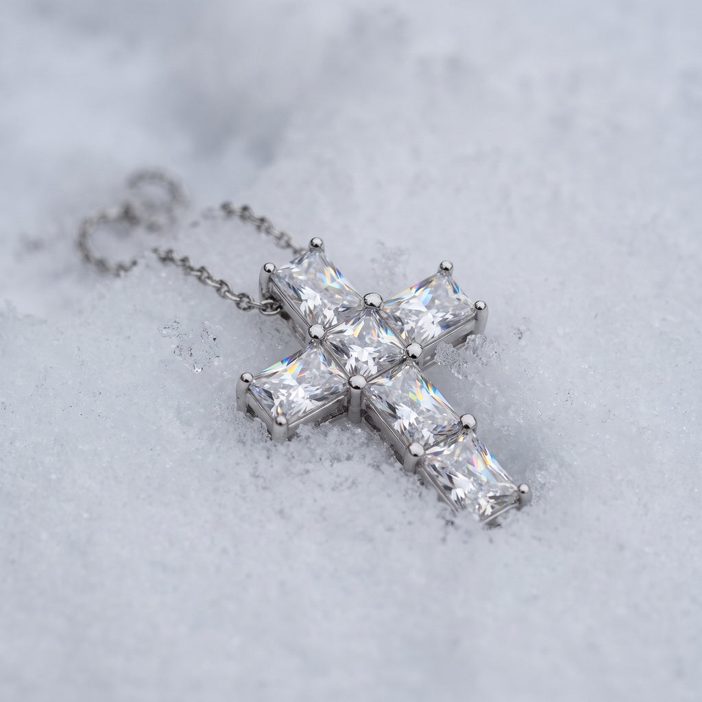 Slim cross pendant resting on snow