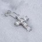 Slim cross pendant resting on snow