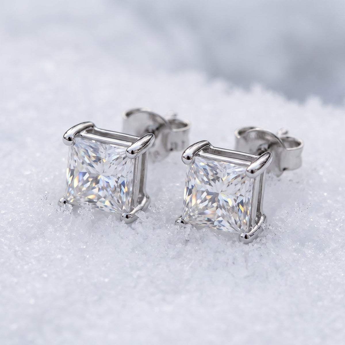 Pair of princess-cut moissanite studs on snow