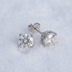 Pair of round moissanite studs on snow