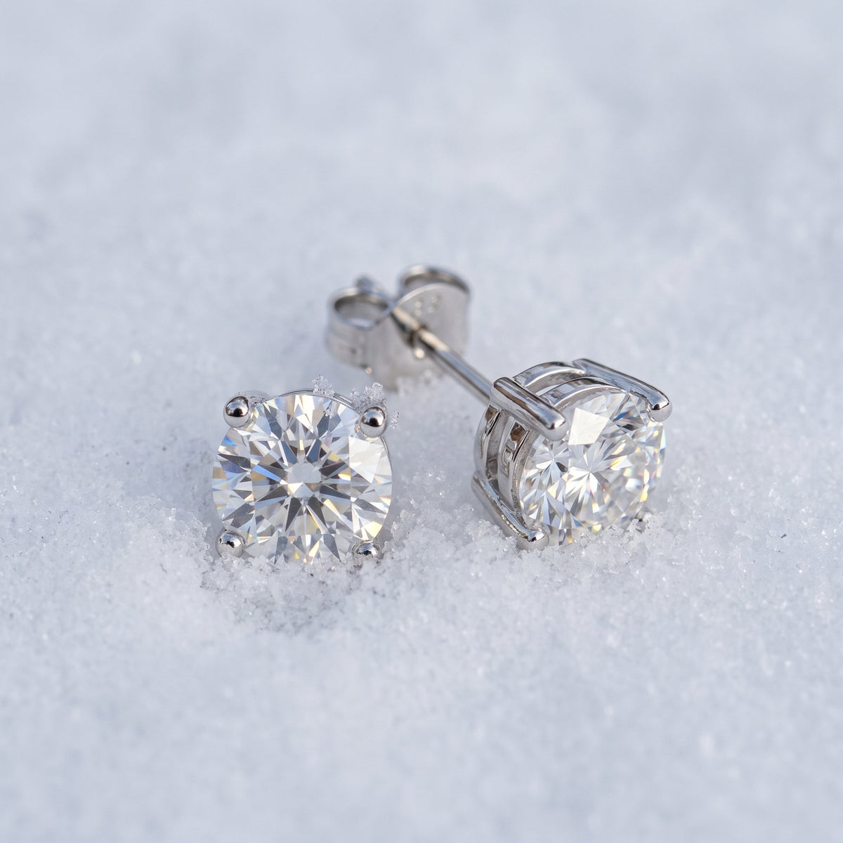 Pair of round moissanite studs on snow