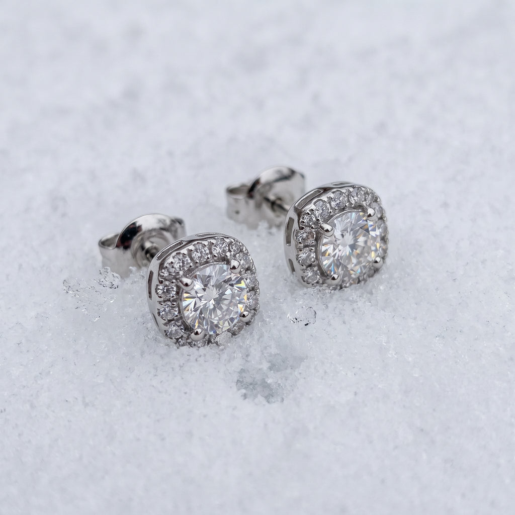 Pair of halo stud earrings on snow