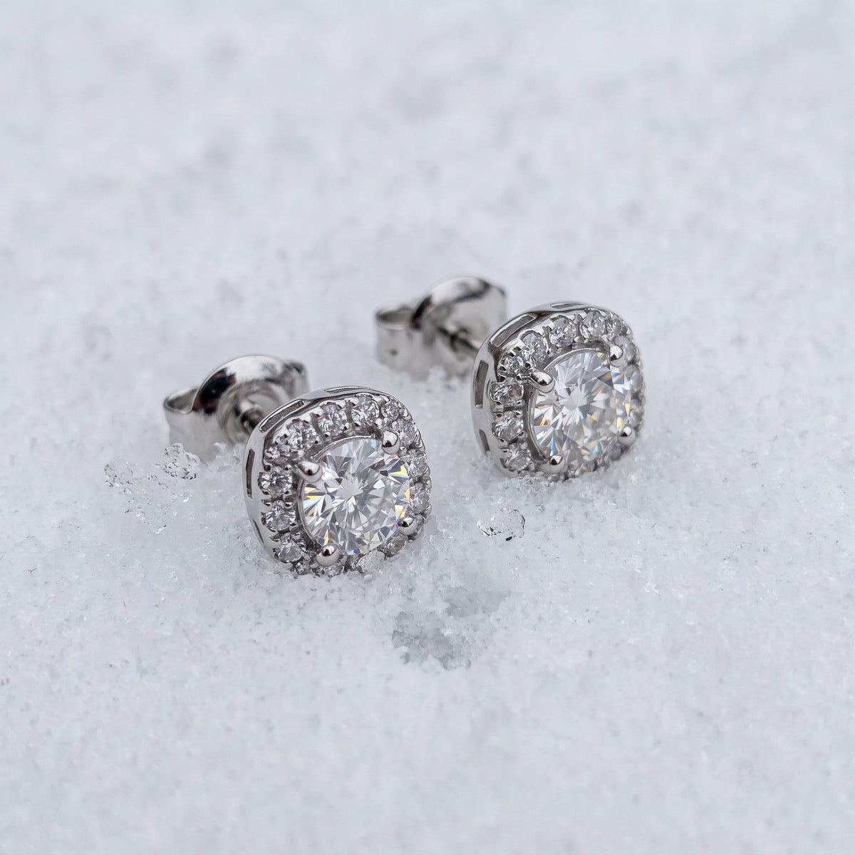 Pair of halo stud earrings on snow
