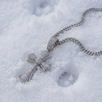 Floral-tip cross pendant on its chain in the snow