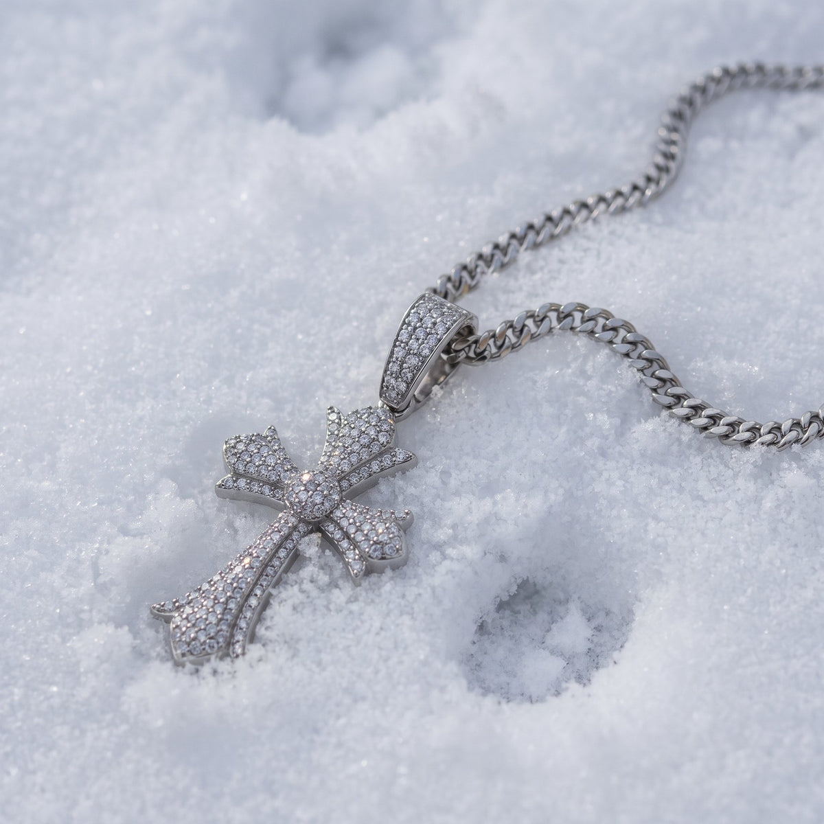 Floral-tip cross pendant on its chain in the snow