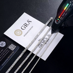 Tennis chains beside a GRA moissanite report card and a handheld gem tester